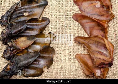 Un groupe d'oreilles de porc et de boeuf séchées sur le burlap. Gâteries à mâcher naturelles pour chiens. Production et commerce de produits pour animaux de compagnie. Vue de dessus. Copier l'espace. Banque D'Images