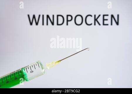Cette photo montre une seringue jetable avec aiguille hypodermique, WINDPOCKEN écrit sur un tableau blanc derrière Banque D'Images