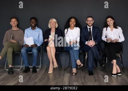 Portrait de groupe souriant des gens d'affaires assis sur des chaises dans la rangée Banque D'Images