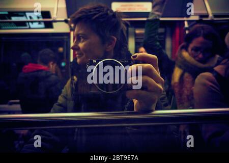 Autoportrait d'une photographe de rue féminine d'un tramway urbain, reflet de la fenêtre du tramway avec d'autres passagers Banque D'Images