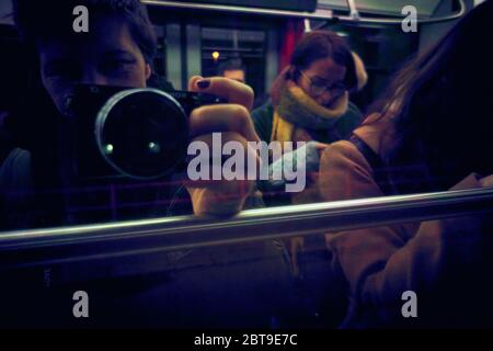 Autoportrait d'une photographe de rue féminine d'un tramway urbain, reflet de la fenêtre du tramway avec d'autres passagers Banque D'Images