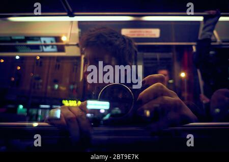 Autoportrait d'une photographe de rue féminine d'un tramway urbain, reflet de la fenêtre du tramway avec d'autres passagers Banque D'Images