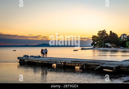 Trois jeunes filles non identifiées profitent d'un coucher de soleil pittoresque à Afissos, en Grèce. Banque D'Images