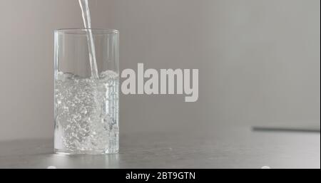 verser de l'eau propre dans le verre du bécher sur le plan de travail en béton Banque D'Images