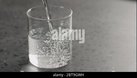 verser de l'eau propre dans le verre du bécher sur le plan de travail en béton Banque D'Images