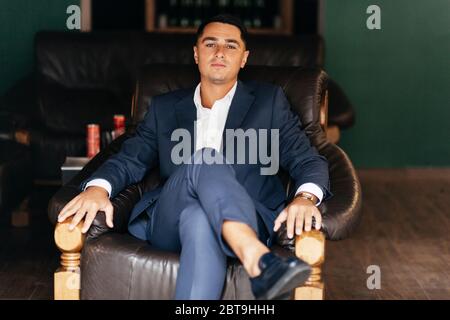 Homme sérieux en chemise blanche et costume assis sur le fauteuil Banque D'Images