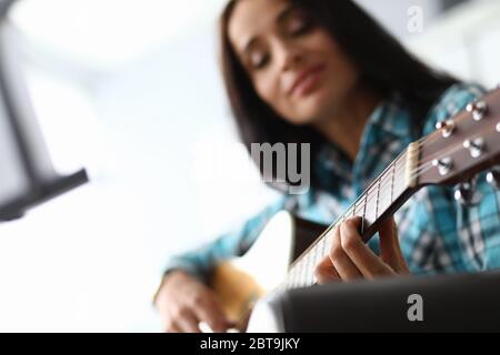 La jeune femme prend des accords de guitare au canapé à la maison Banque D'Images