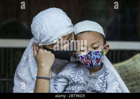 Une femme musulmane avec son fils est vue porter des masques faciaux pendant les prières d'Eid al-Fitr tenues à leur domicile. Alors que des millions de pays musulmans accueillent Eid al-Fitr comme signe de la fin du ramadan en jeûnant dans la pandémie toujours croissante du coronavirus, le gouvernement indonésien a demandé aux musulmans de faire leurs prières d'Eid à partir de leurs foyers pour prévenir la propagation du coronavirus. Banque D'Images