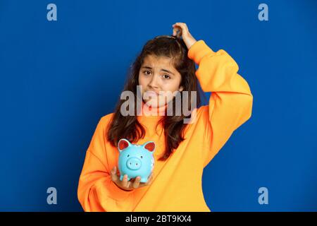 Adorable jeune fille de prètine avec jersey jaune sur fond bleu Banque D'Images