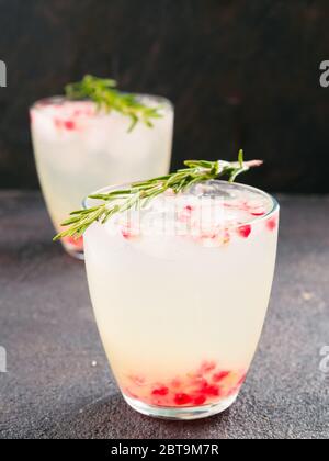 L'automne et l'hiver blanc - idée cocktails sangria avec le romarin, le jus de citron et pomegrante sur fond de ciment noir. Banque D'Images