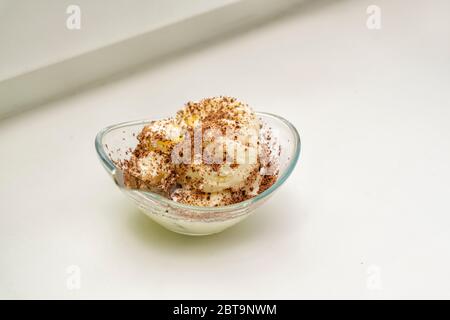 Bol avec glace à la vanille parsemée de copeaux de chocolat sur une table sur fond clair Banque D'Images