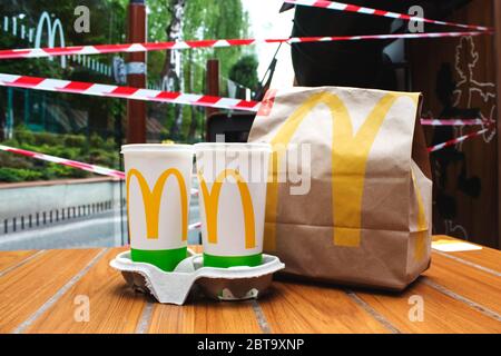Lviv, Ukraine - 17 mai 2020 : restaurant McDonalds, deux tasses et sac en papier avec nourriture sur table en bois avec bandes protectrices sur fond. Rouvrir conc Banque D'Images