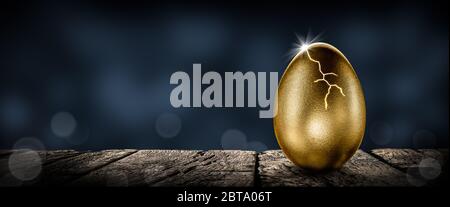 Oeuf de Nest d'or brillant sur la table en bois fissuration ouverte avec la rupture de lumière - investissement maturité concept Banque D'Images