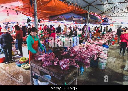 Bac Ha, Vietnam, 7 janvier 2020 - Boucher à bac Ha Market saling la viande crue sur sa table noire en bois Banque D'Images