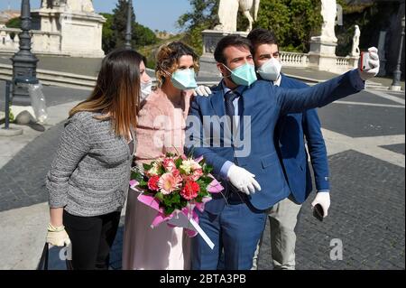 Rome, Italie - 05 avril 2020 : les jeunes mariés prennent un selfie avec des témoins de mariage. Le gouvernement italien a imposé des restrictions sans précédent pour stopper la propagation du coronavirus COVID-19, entre autres mesures, les mouvements de personnes sont autorisés uniquement pour le travail, l'achat de biens essentiels et pour des raisons de santé. Seuls les conjoints et les témoins de mariage sont autorisés à participer aux mariages. Crédit: Nicolò Campo/Alay Live News Banque D'Images