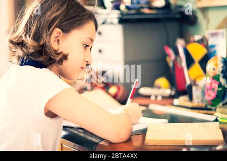 Jeune fille travaillant à la maison sur son bureau Banque D'Images