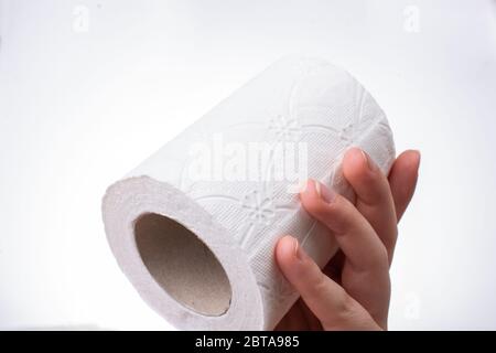 Une main féminine prend un rouleau de papier toilette blanc à la main. Banque D'Images