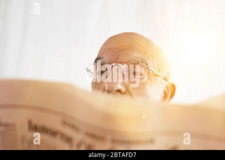 Senior Homme lisant son journal financier avec soleil Banque D'Images