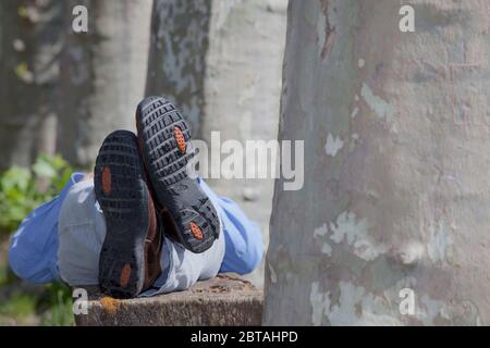 Homme d'affaires allongé sur un banc dans un parc - se concentrer sur les chaussures Banque D'Images