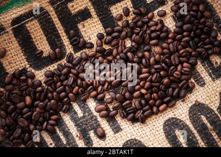 Les grains de café rôtis sont en tissu de sac de jute avec un texte noir standard. Photo à plat, arrière-plan de la vue de dessus Banque D'Images