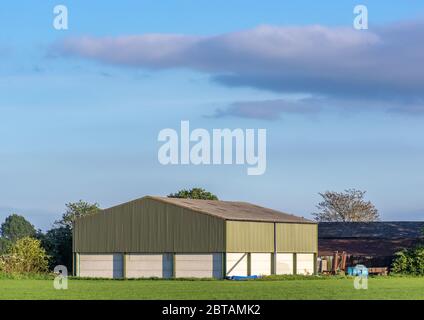 Construction de ferme préfabriquée dans un cadre rural par une journée ensoleillée avec ciel bleu. Banque D'Images