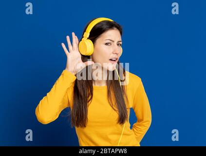 Brunette, jeune femme, porte un T-shirt jaune sur fond bleu Banque D'Images