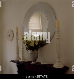 Miroir circulaire au-dessus de la cheminée avec chandeliers blancs Banque D'Images