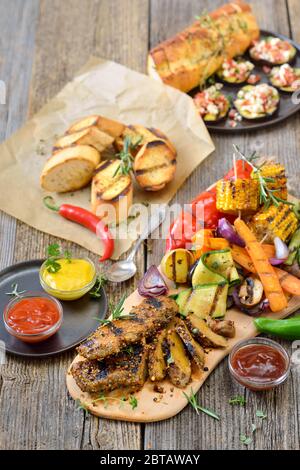 Steaks seitan grillés aux légumes mélangés, sauces épicées et baguette croustillante Banque D'Images