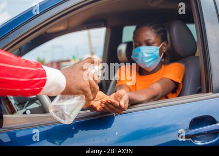 Femme en voiture recevant du gel d'alcool ou du gel désinfectant pour se laver les mains, le virus corona ou la protection Covid-19. Banque D'Images