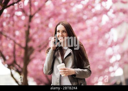 Portrait d'une belle fille dans un arbre de sakura. Discuter au téléphone. Arbre japonais Banque D'Images