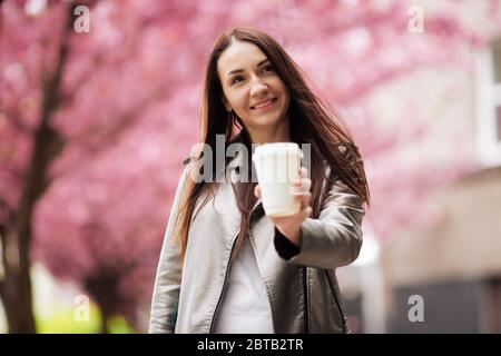 Portrait en gros plan d'une fille de brunette sur un fond de cerisier japonais. Banque D'Images