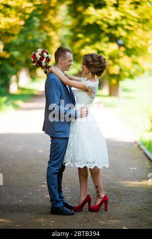 Couple de mariage, jeunes mariés heureux et mari qui s'embrasse dans le parc vert. Banque D'Images