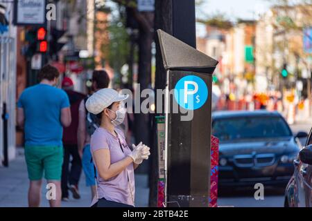 Montréal, CA - 23 mai 2020 : femme asiatique avec masque et gants pour la protection contre le COVID-19 payant son billet de stationnement Banque D'Images