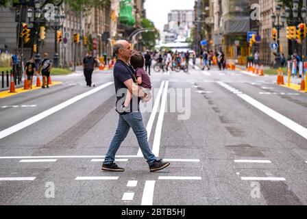 Un homme avec un enfant dans ses bras traversant la route piétonne spécifiée de via Laietana.le Conseil municipal de Barcelone met en place des plateformes piétonnes pour améliorer les mesures de distance sociale dues à la pandémie Covid-19 et récupère de grandes avenues pour l'utilisation des piétons les week-ends. Banque D'Images