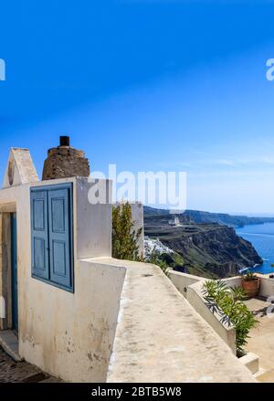 Île de Santorin, Grèce. Architecture traditionnelle, entrée de la maison, terrasse et vue sur la caldeira sur la mer Égée, ciel bleu clair, mer calme Banque D'Images