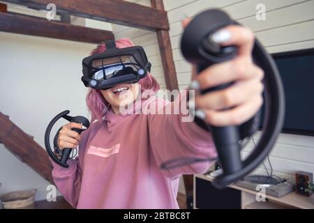 Excitée adolescence hipster fille jouant la réalité virtuelle jeu vidéo porter des lunettes vr. Banque D'Images