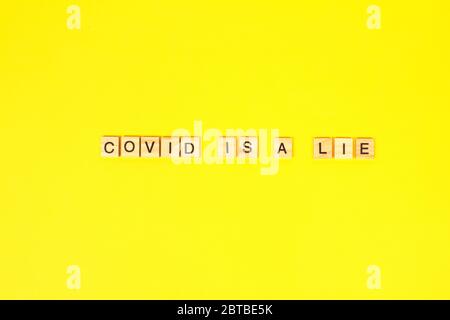 Covid est un mensonge - inscription écrite avec des lettres noires sur des blocs de bois sur fond jaune vif avec un espace de copie. Après la crise de quarantaine Covid-19 Banque D'Images