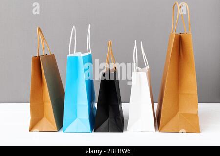 Assortiment de sacs en papier pour radeau de couleurs. Shopping maquette sacs de papier paquets sur fond blanc table gris avec espace de copie. Shopping, vente Banque D'Images