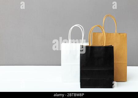 Assortiment de sacs en papier pour radeau de couleurs. Shopping maquette sacs de papier paquets sur fond blanc table gris avec espace de copie. Shopping, vente Banque D'Images