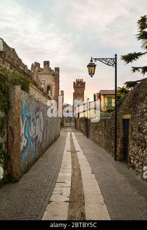 Une ruelle étroite dans la vieille ville avec le château médiéval Scaliger et les remparts de la ville, Lazise, Vérone, Vénétie, Italie Banque D'Images