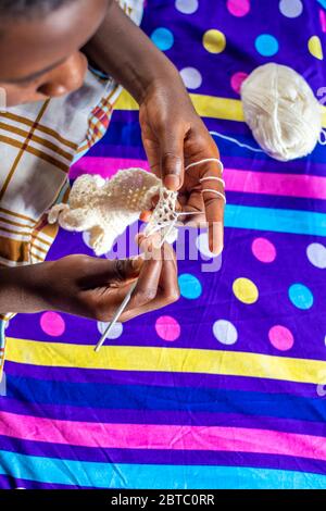 un garçon africain adore tricoter à la maison, les mains seulement vue du dessus Banque D'Images