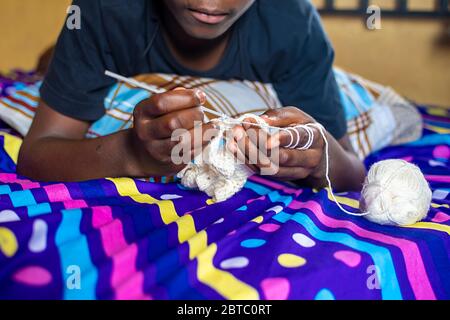 un adolescent africain adore tricoter à la maison Banque D'Images