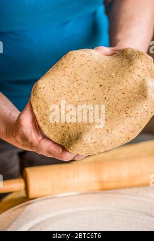 Étirez la pâte à pizza multigrains sur vos mains pour faire une pizza à croûte mince Banque D'Images