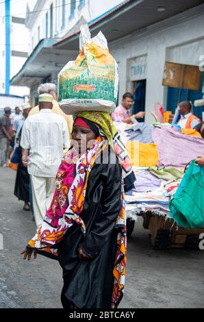 Femme portant un sac sur sa tête dans une rue à Mombasa Banque D'Images