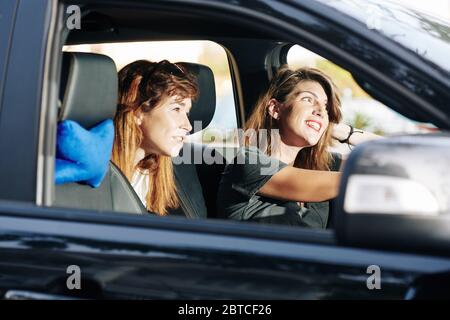Des amies joyeuses, qui apprécient la voiture et parlent bien le dimanche Banque D'Images