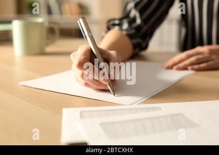 Gros plan des mains de femme écrivant la lettre dans la nuit sur un bureau à la maison Banque D'Images