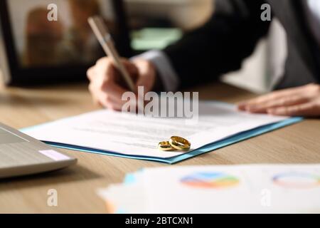 Gros plan de la femme freelance mains signe des papiers de divorce assis sur un bureau à la maison la nuit Banque D'Images