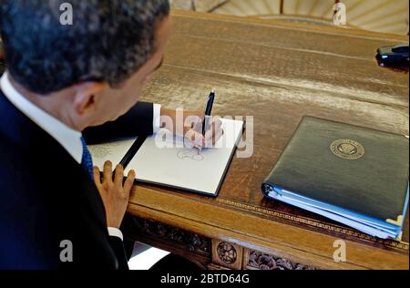 Le président Barack Obama écrit à son bureau dans le bureau ovale 3/3/09. Banque D'Images