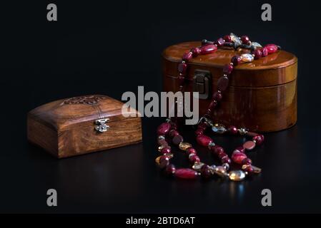 Deux anciens bijoux en bois et un collier de perles de verre isolé sur fond noir. Boîtes en bois pour différentes décorations ou de petites carabines Banque D'Images