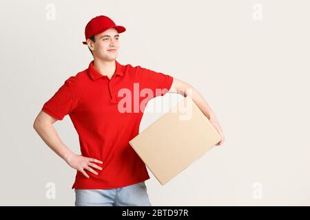 Livraison à temps. Un coursier souriant tient une grande boîte Banque D'Images